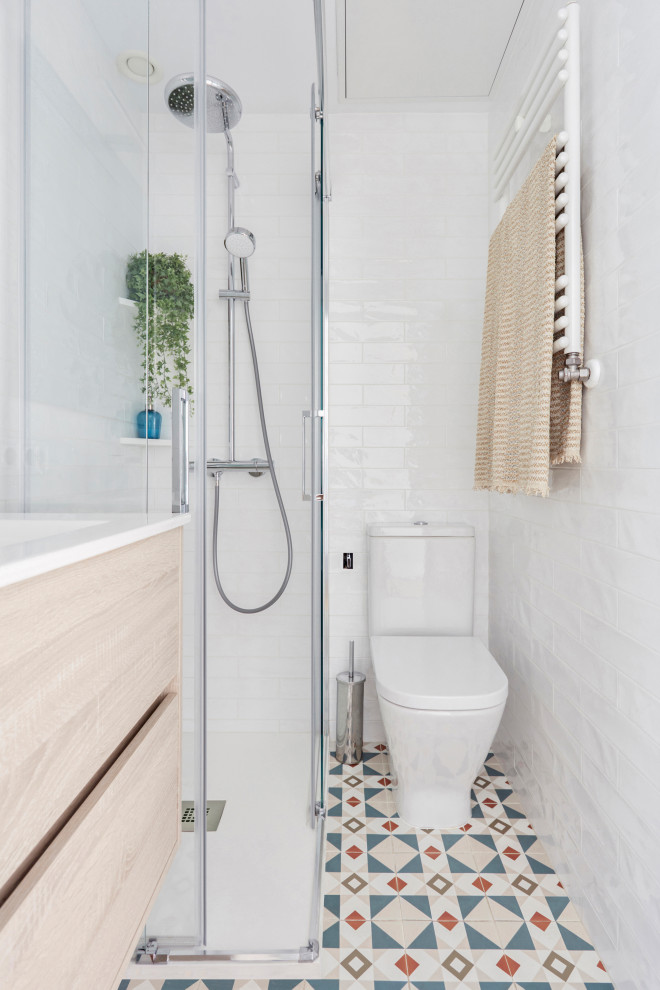 Foto på ett funkis vit badrum, med släta luckor, skåp i ljust trä, en hörndusch, flerfärgat golv och dusch med skjutdörr