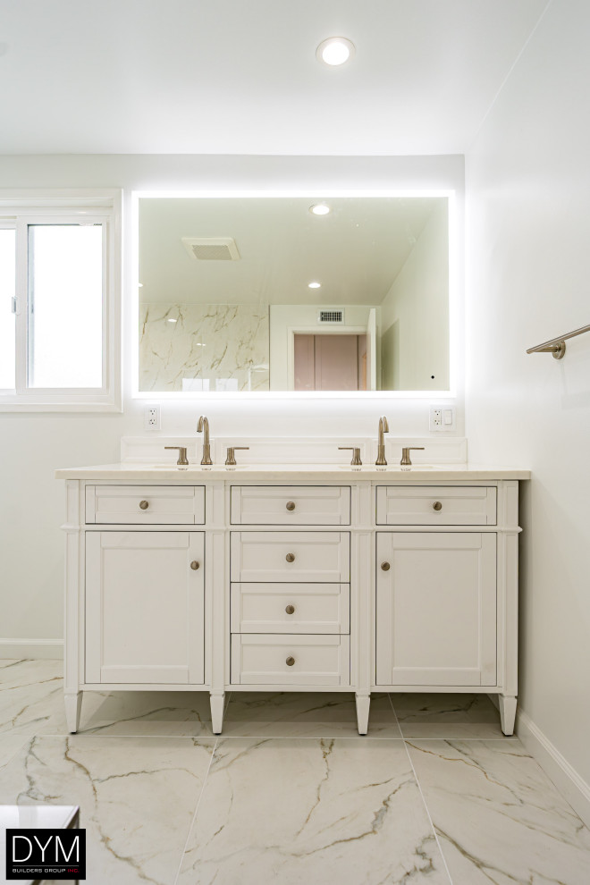 Foto på ett stort funkis vit en-suite badrum, med luckor med profilerade fronter, vita skåp, en toalettstol med hel cisternkåpa, vit kakel, marmorkakel, vita väggar, marmorgolv, ett nedsänkt handfat, bänkskiva i akrylsten, vitt golv, dusch med gångjärnsdörr och en dusch/badkar-kombination
