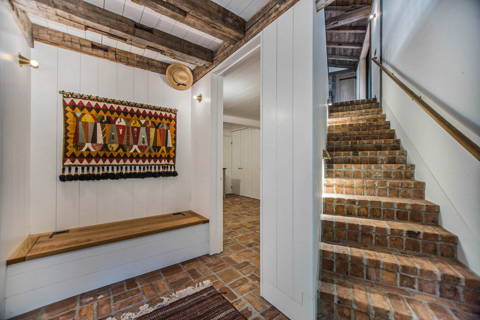 Foyer - rustic brick floor, red floor, exposed beam and shiplap wall foyer idea in Grand Rapids with white walls