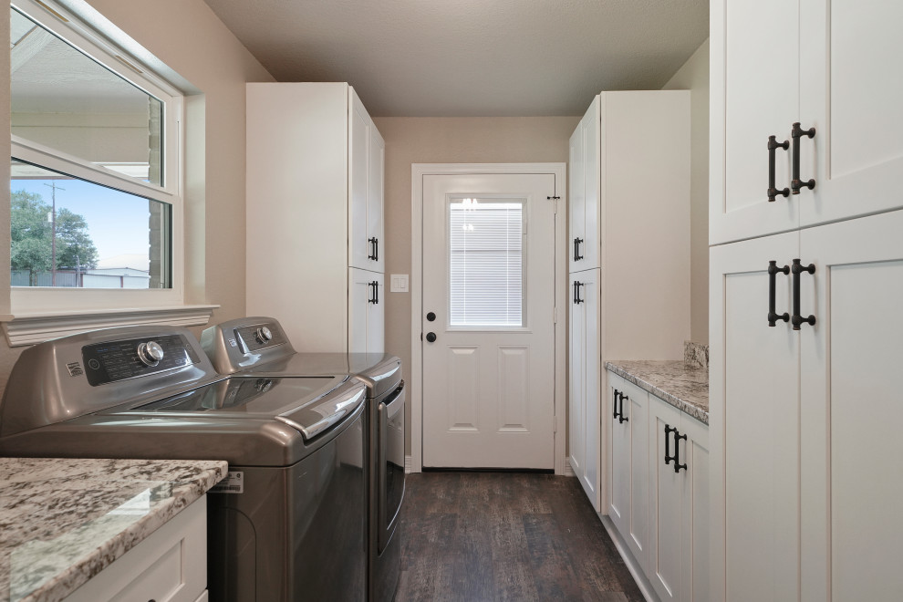 Design ideas for a large arts and crafts laundry room in Houston with a farmhouse sink, shaker cabinets, distressed cabinets, granite benchtops, beige splashback, porcelain splashback, dark hardwood floors, brown floor and brown benchtop.