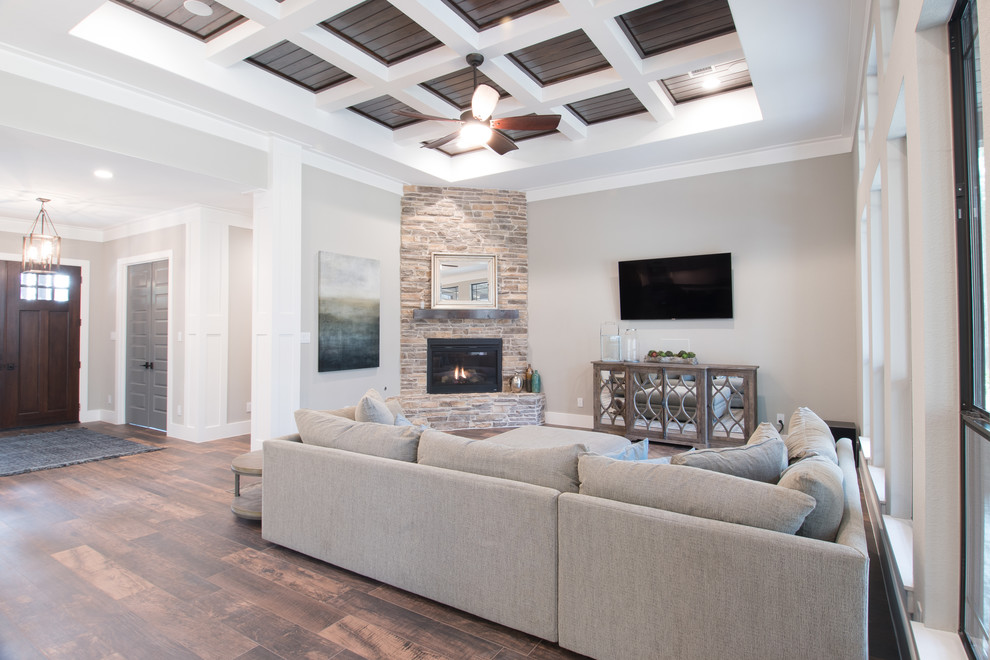 Inspiration for a mid-sized country formal open concept living room in Houston with grey walls, dark hardwood floors, a corner fireplace, a stone fireplace surround, a wall-mounted tv and brown floor.