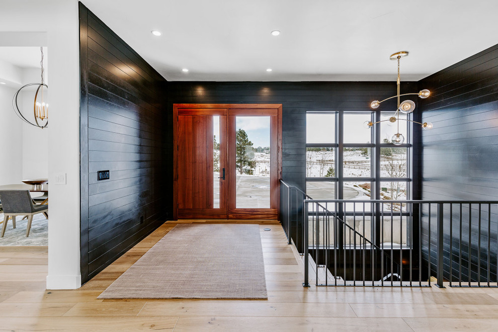 Inspiration for a large transitional light wood floor and brown floor foyer remodel in Denver with black walls and a dark wood front door