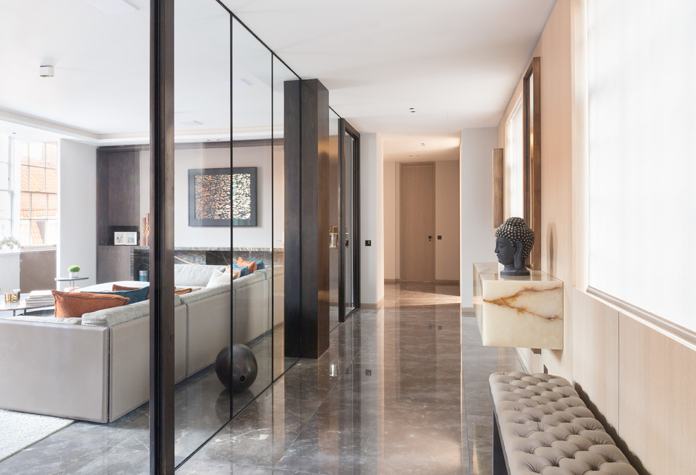 Inspiration for a large contemporary hallway in London with beige walls and marble floors.