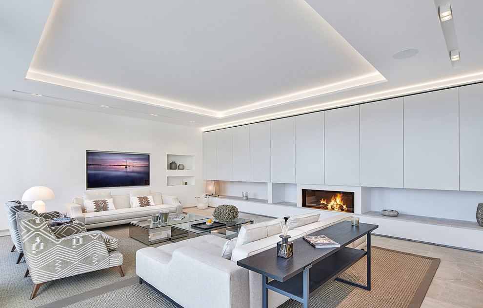 This is an example of a large contemporary formal open concept living room in Palma de Mallorca with white walls, a ribbon fireplace, a wall-mounted tv and beige floor.