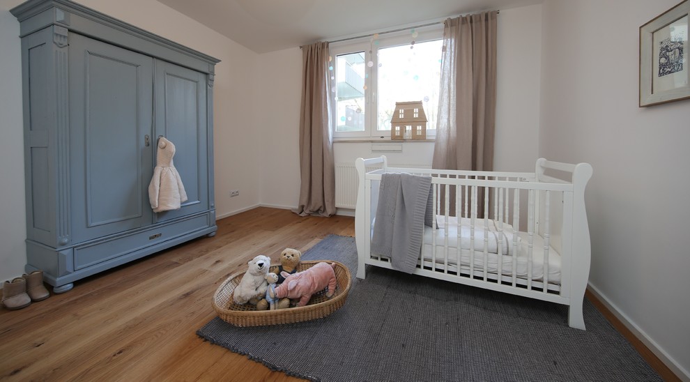 Design ideas for a mid-sized contemporary gender-neutral nursery in Munich with white walls, medium hardwood floors and brown floor.
