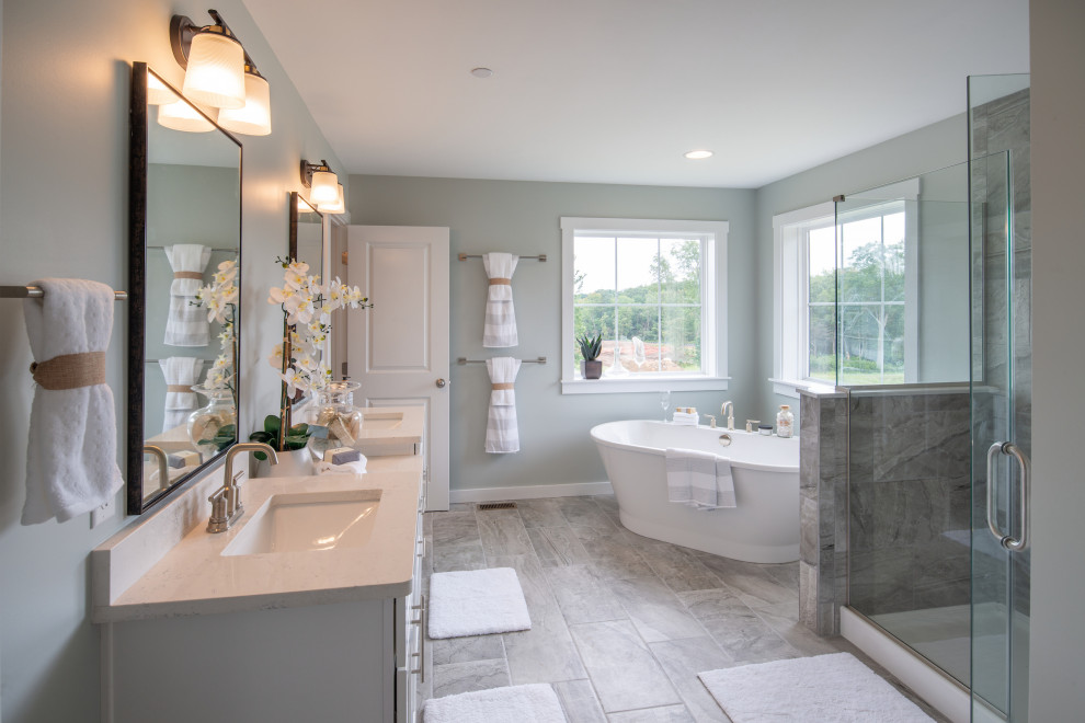 This is an example of a traditional ensuite bathroom in Baltimore with shaker cabinets, white cabinets, a freestanding bath, an alcove shower, multi-coloured tiles, grey walls, a submerged sink, engineered stone worktops, grey floors, a hinged door, white worktops, double sinks and a built in vanity unit.