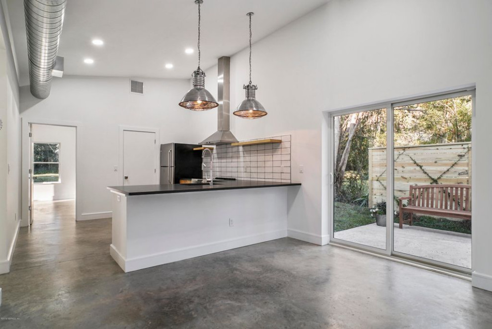 Large modern l-shaped open plan kitchen in Other with an integrated sink, flat-panel cabinets, medium wood cabinets, quartzite benchtops, white splashback, cement tile splashback, stainless steel appliances, concrete floors, grey floor, black benchtop and vaulted.