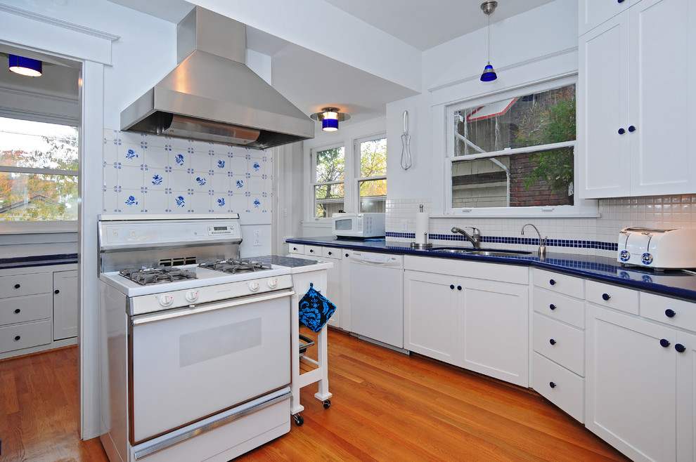 Kitchen pantry - mid-sized transitional u-shaped medium tone wood floor kitchen pantry idea in Seattle with a double-bowl sink, shaker cabinets, white cabinets, solid surface countertops, blue backsplash, ceramic backsplash, white appliances, white walls and no island