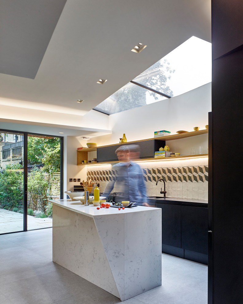 This is an example of a medium sized contemporary cream and black l-shaped kitchen/diner in London with an integrated sink, flat-panel cabinets, black cabinets, composite countertops, multi-coloured splashback, ceramic splashback, black appliances, porcelain flooring, an island, grey floors, white worktops, a coffered ceiling and feature lighting.