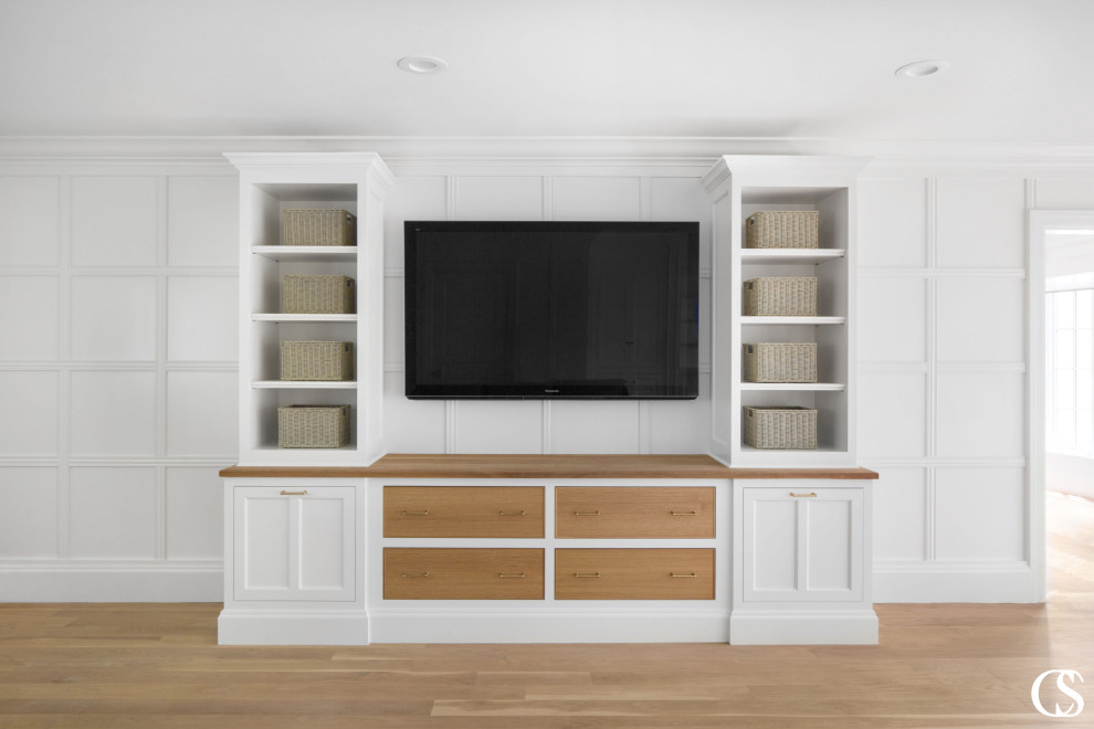 Modelo de salón abierto clásico renovado grande sin chimenea con paredes blancas, suelo de madera clara, televisor colgado en la pared y panelado
