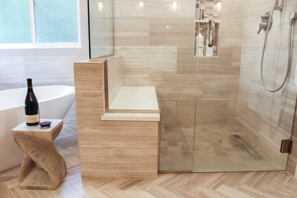 Freestanding bathtub - large transitional master limestone tile limestone floor and beige floor freestanding bathtub idea in Denver with shaker cabinets, brown cabinets, gray walls, an undermount sink, quartz countertops and a hinged shower door