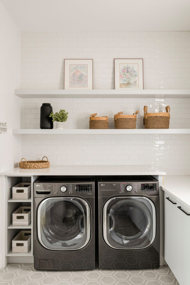 Mid-sized contemporary laundry room in Calgary with an undermount sink, flat-panel cabinets, grey cabinets, quartz benchtops, white splashback, ceramic splashback, porcelain floors, a side-by-side washer and dryer, grey floor and white benchtop.