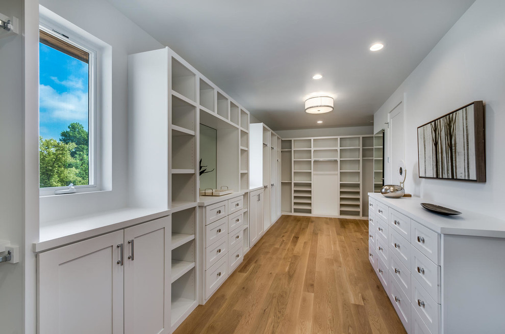 This is an example of a large transitional gender-neutral walk-in wardrobe in Denver with shaker cabinets, white cabinets and medium hardwood floors.