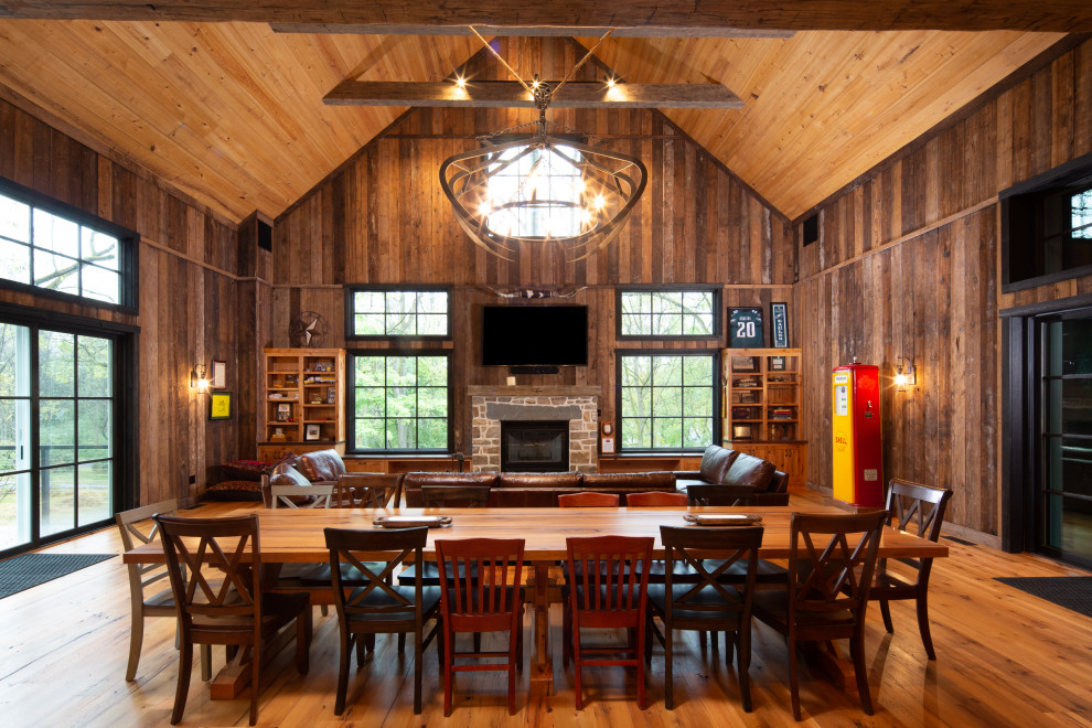 Large country open plan dining in Philadelphia with brown walls, medium hardwood floors, a standard fireplace, brown floor, exposed beam, vaulted, wood and wood walls.