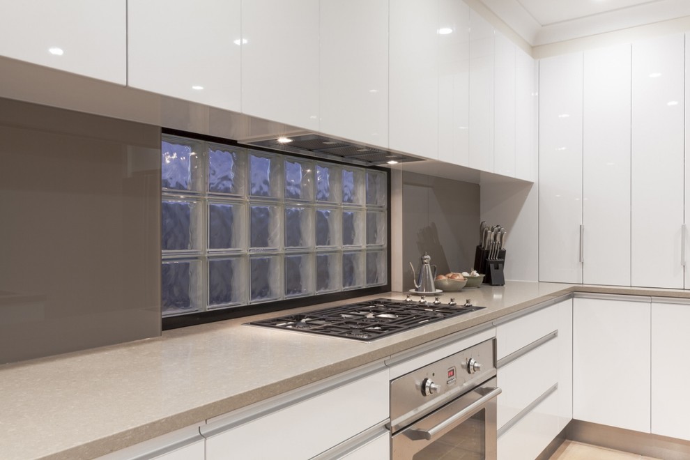 This is an example of a mid-sized l-shaped kitchen pantry in Other with a single-bowl sink, flat-panel cabinets, white cabinets, tile benchtops, white splashback, subway tile splashback, white appliances, marble floors and with island.