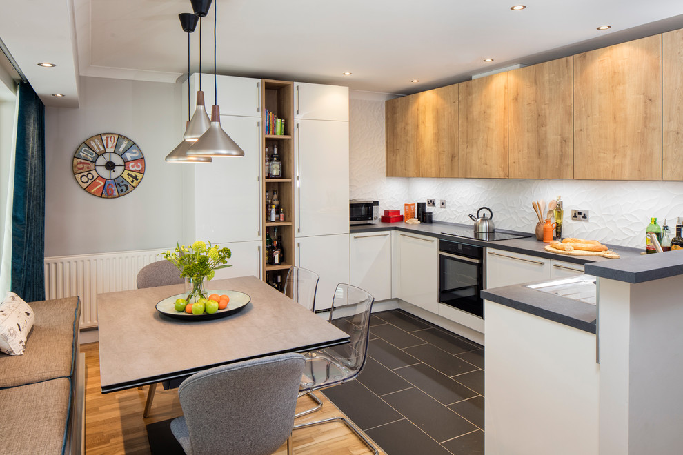 This is an example of a mid-sized contemporary u-shaped open plan kitchen in Dublin with an integrated sink, flat-panel cabinets, light wood cabinets, laminate benchtops, white splashback, ceramic splashback, stainless steel appliances, ceramic floors and no island.