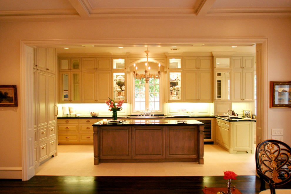 Design ideas for an expansive traditional u-shaped eat-in kitchen in Houston with an undermount sink, raised-panel cabinets, beige cabinets, granite benchtops, beige splashback, limestone floors, with island and panelled appliances.