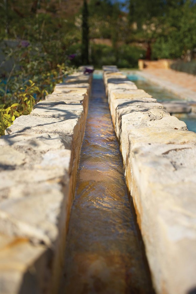 Photo of a mediterranean backyard partial sun garden in Orange County with a water feature.