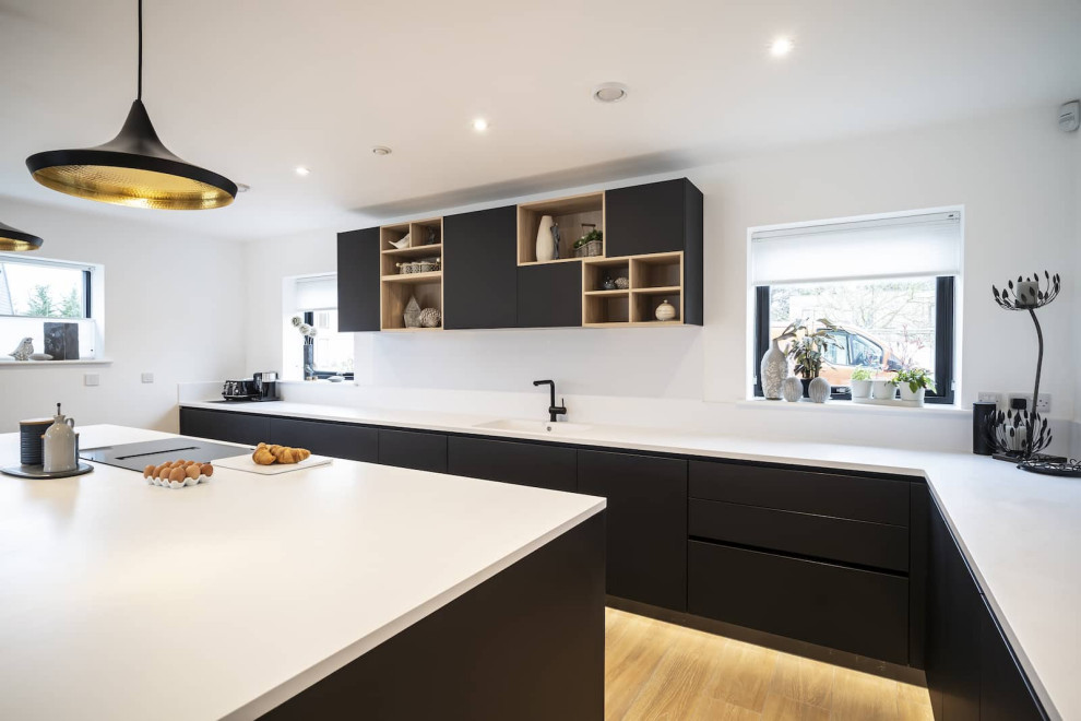 Inspiration for a large scandinavian l-shaped light wood floor and brown floor open concept kitchen remodel in Oxfordshire with flat-panel cabinets, black cabinets, quartzite countertops, white backsplash, black appliances, an island and yellow countertops