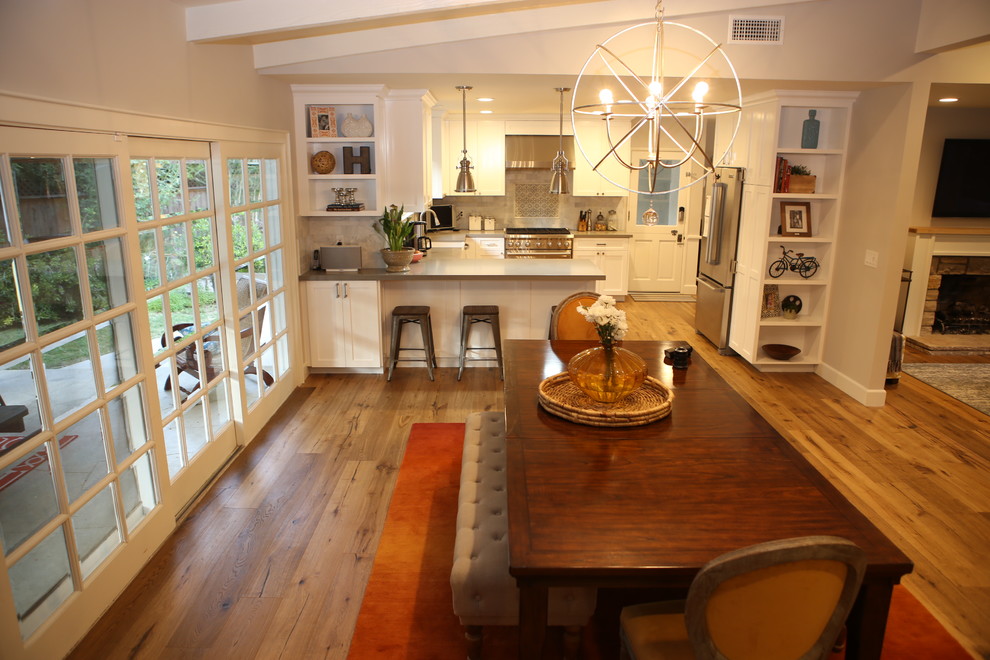 Design ideas for a large country u-shaped eat-in kitchen in Los Angeles with raised-panel cabinets, white cabinets, stainless steel appliances, medium hardwood floors, no island, a farmhouse sink, quartz benchtops, porcelain splashback, white splashback, brown floor and grey benchtop.