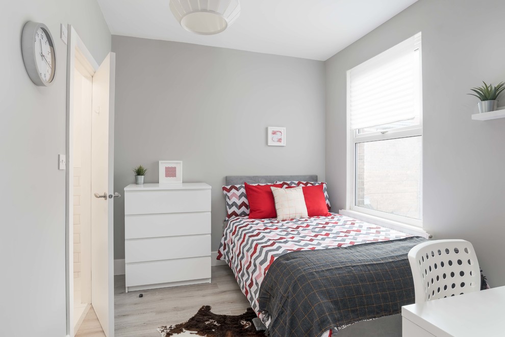 This is an example of a small eclectic guest bedroom in Other with grey walls, laminate floors and grey floor.