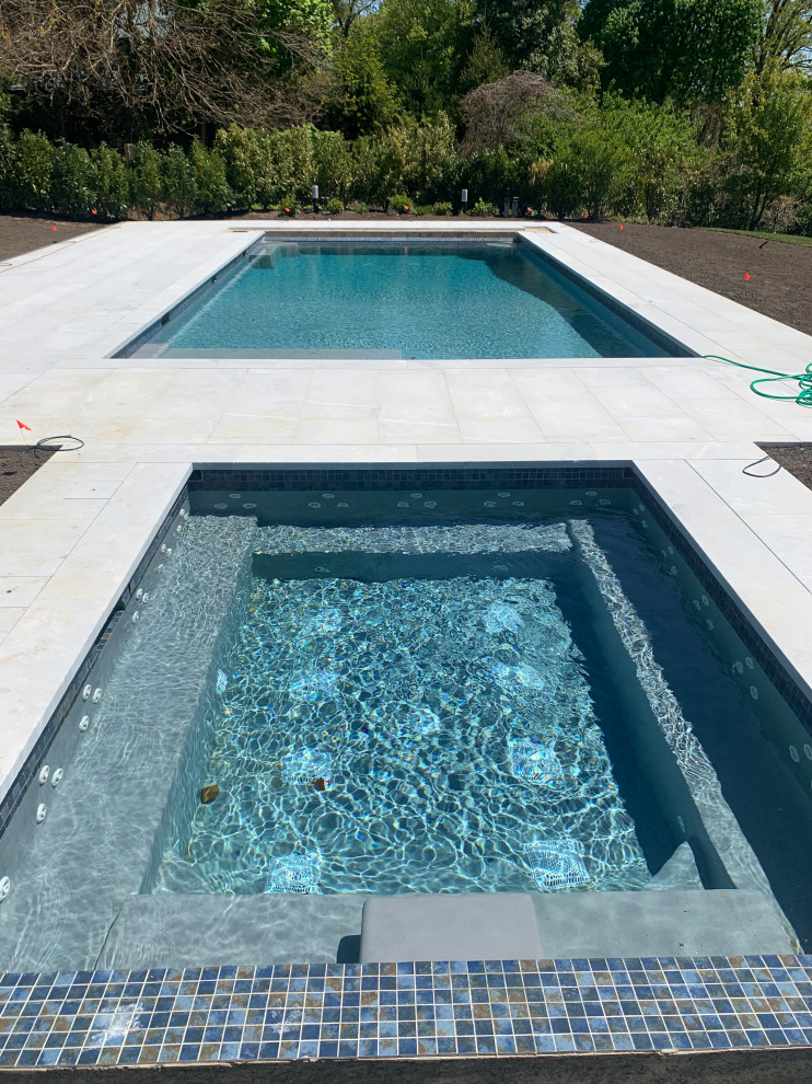 Ispirazione per una grande piscina naturale rettangolare dietro casa con una vasca idromassaggio e pavimentazioni in pietra naturale
