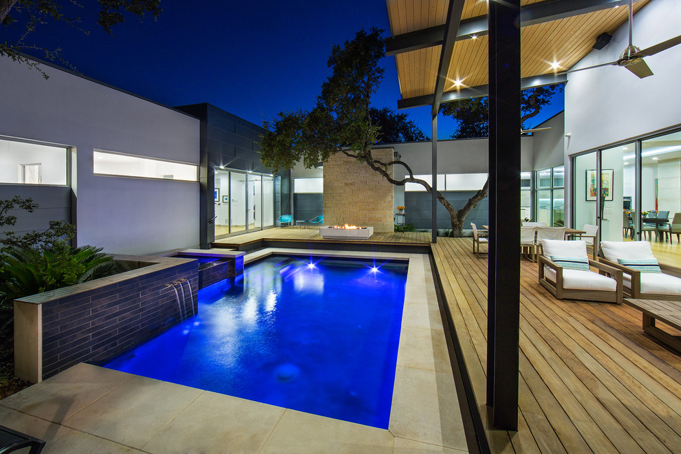 Photo of a small modern courtyard rectangular lap pool in Austin with a hot tub and natural stone pavers.