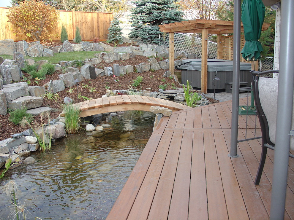 Design ideas for a large contemporary backyard partial sun formal garden for winter in Calgary with decking.
