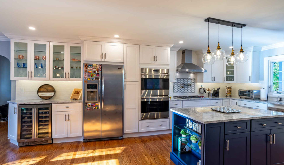 Eat-in kitchen - mid-sized transitional u-shaped medium tone wood floor and brown floor eat-in kitchen idea in Philadelphia with a farmhouse sink, shaker cabinets, blue cabinets, quartz countertops, white backsplash, porcelain backsplash, stainless steel appliances, an island and gray countertops