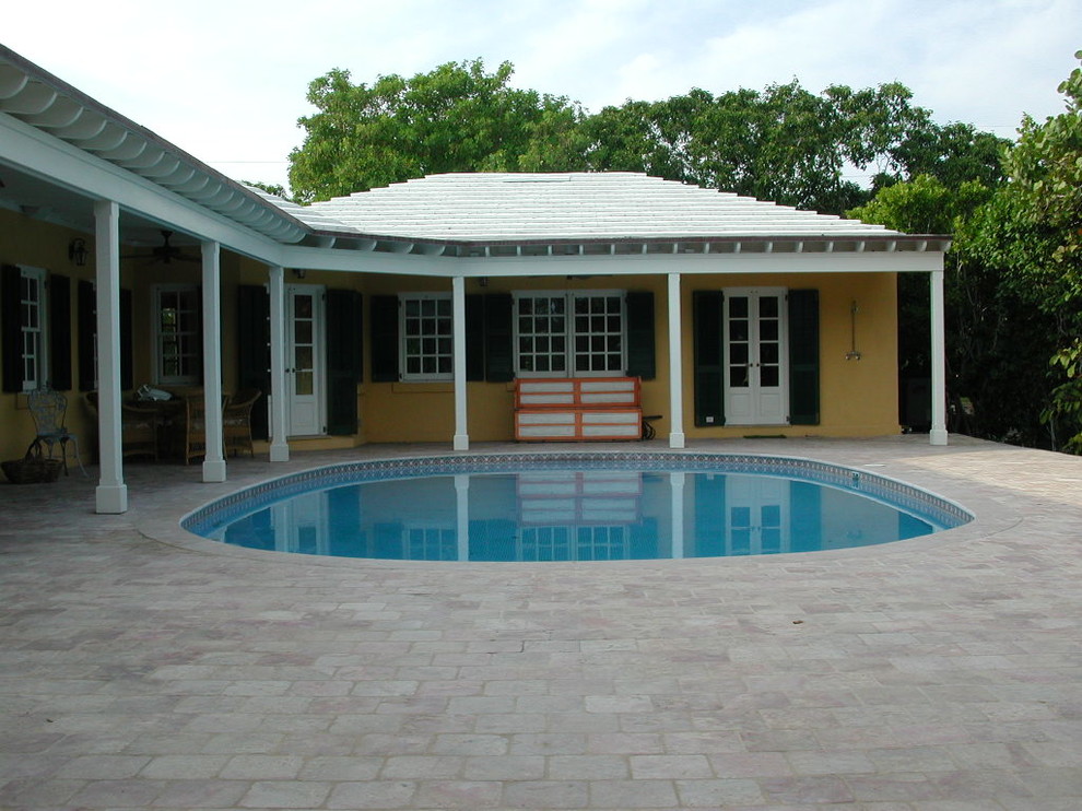 Photo of a mid-sized traditional courtyard round pool in Miami with natural stone pavers.