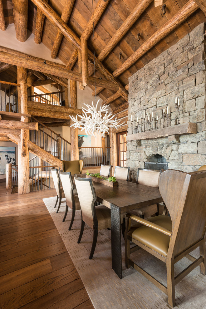 Mountain style dark wood floor dining room photo with a standard fireplace and a stone fireplace