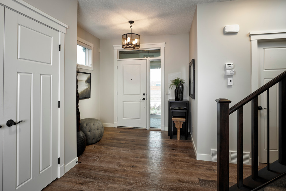 Foyer - transitional medium tone wood floor foyer idea in Calgary with white walls and a white front door