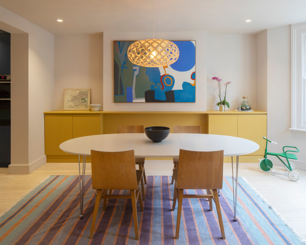 Offene, Einzeilige, Große Moderne Küche mit flächenbündigen Schrankfronten, gelben Schränken, hellem Holzboden und Kücheninsel in London