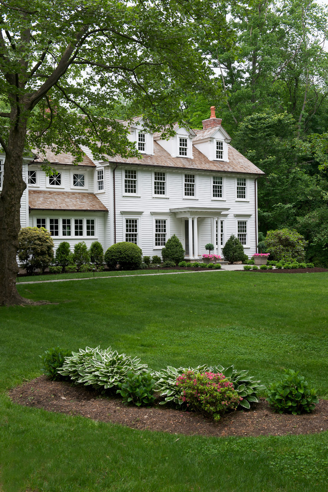 Photo of a traditional three-storey white exterior in New York with a gable roof and vinyl siding.