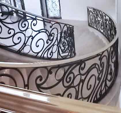 Large traditional wood curved staircase in DC Metro with wood risers and metal railing.