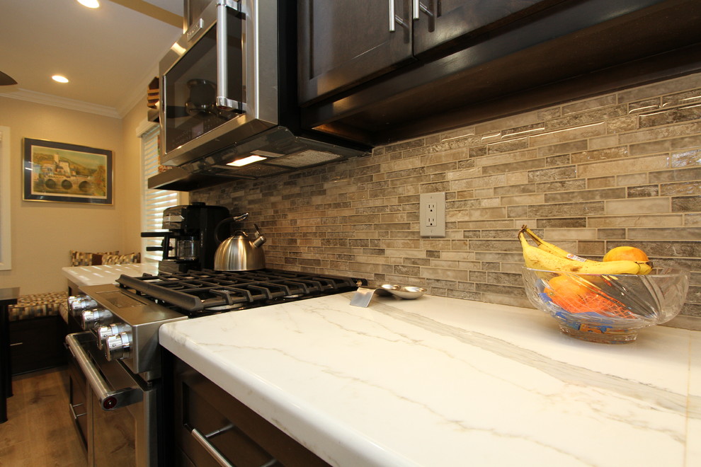 Small transitional l-shaped light wood floor and beige floor open concept kitchen photo in Orange County with an undermount sink, shaker cabinets, dark wood cabinets, quartz countertops, beige backsplash, glass sheet backsplash, stainless steel appliances and no island