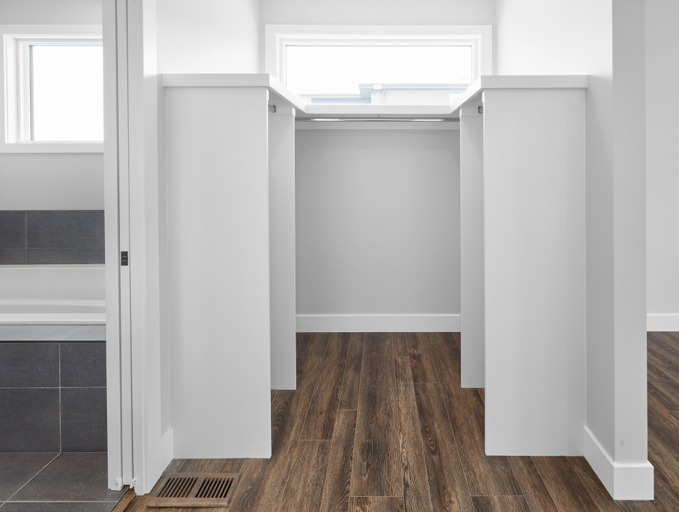 Inspiration for a large modern gender-neutral storage and wardrobe in Edmonton with medium hardwood floors and brown floor.