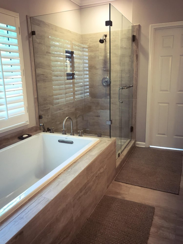 Design ideas for a mid-sized traditional master bathroom in Other with a drop-in tub, a corner shower, a one-piece toilet, beige tile, cement tile, beige walls, porcelain floors, an undermount sink, a hinged shower door, a double vanity and a floating vanity.