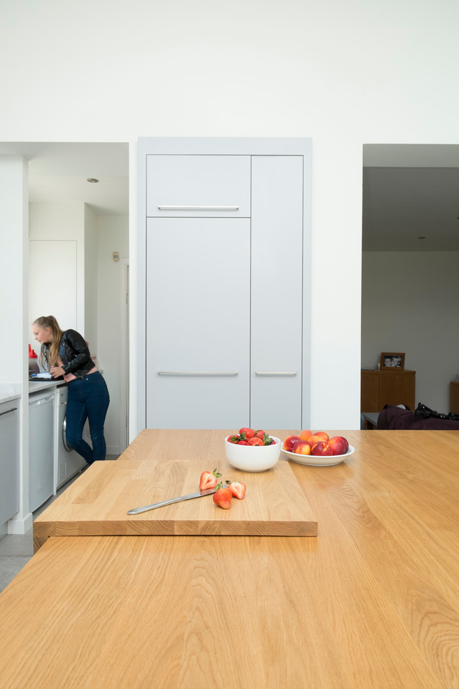 Inspiration for a mid-sized contemporary single-wall eat-in kitchen in Cardiff with a drop-in sink, flat-panel cabinets, grey cabinets, solid surface benchtops, glass sheet splashback, stainless steel appliances, ceramic floors and with island.