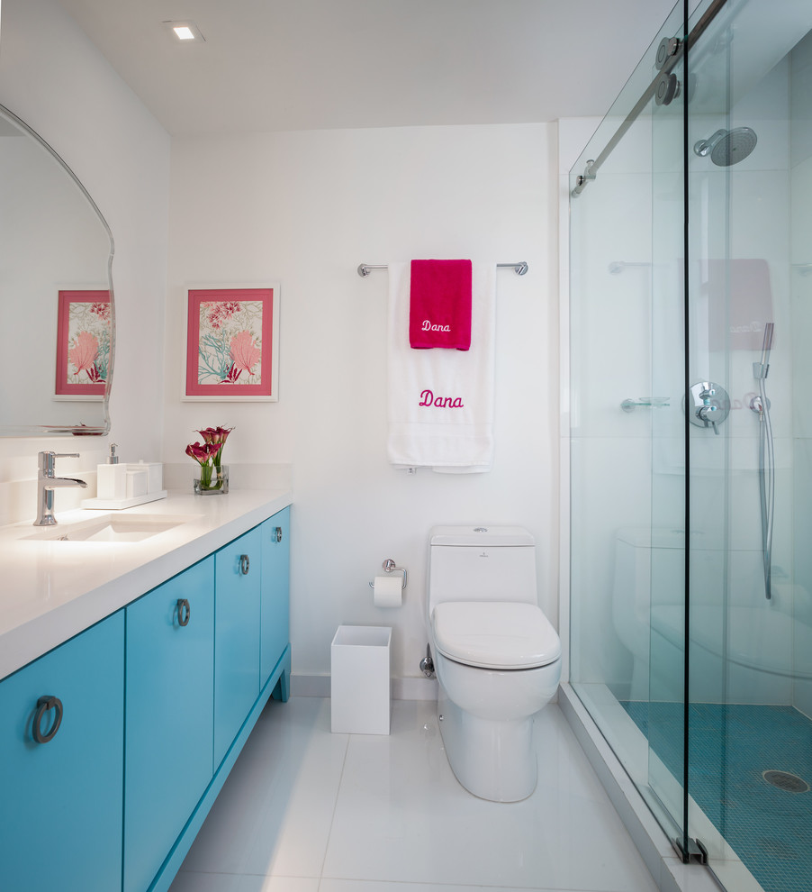 Inspiration for a mid-sized contemporary kids bathroom in Miami with an integrated sink, flat-panel cabinets, blue cabinets, an alcove shower, a one-piece toilet, white tile, white walls, solid surface benchtops and white benchtops.