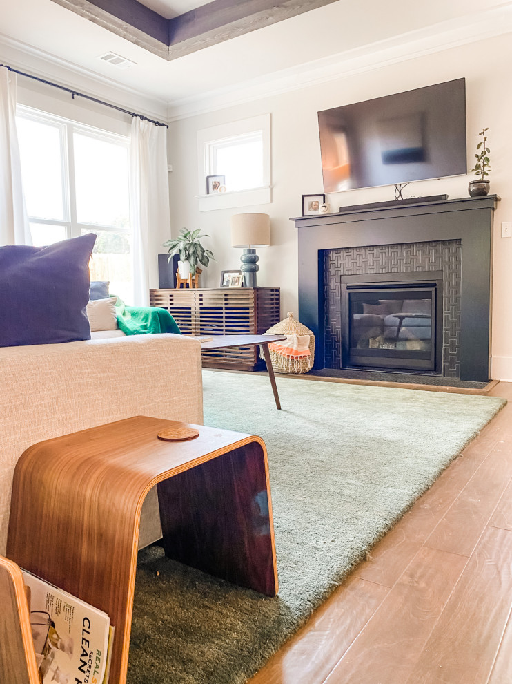Cette photo montre un salon rétro de taille moyenne et ouvert avec un mur gris, un sol en bois brun, une cheminée standard, un manteau de cheminée en bois et un téléviseur fixé au mur.