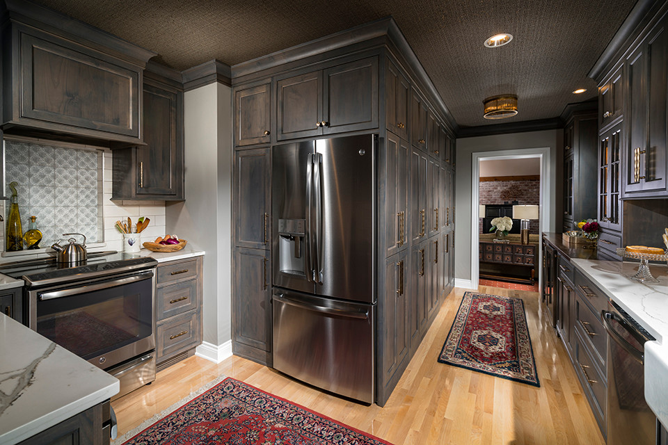 Inspiration for a transitional light wood floor kitchen remodel with a farmhouse sink, gray cabinets, quartz countertops, white backsplash, subway tile backsplash and stainless steel appliances