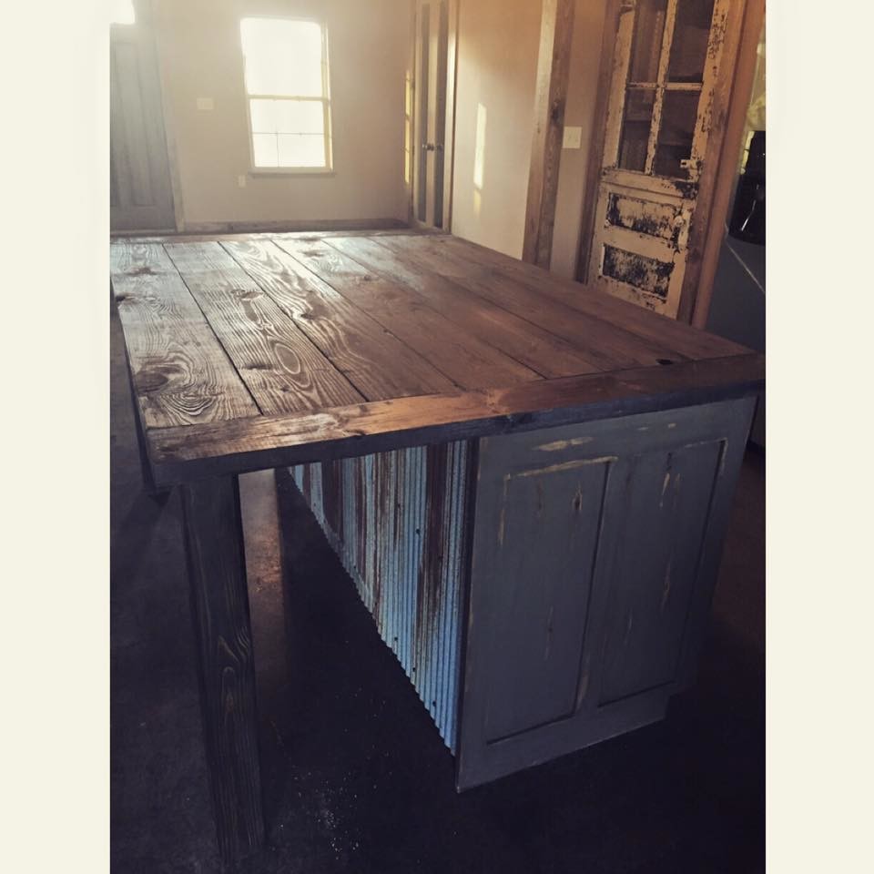Example of a large mountain style concrete floor kitchen design with flat-panel cabinets, medium tone wood cabinets, wood countertops, beige backsplash, stone tile backsplash and an island