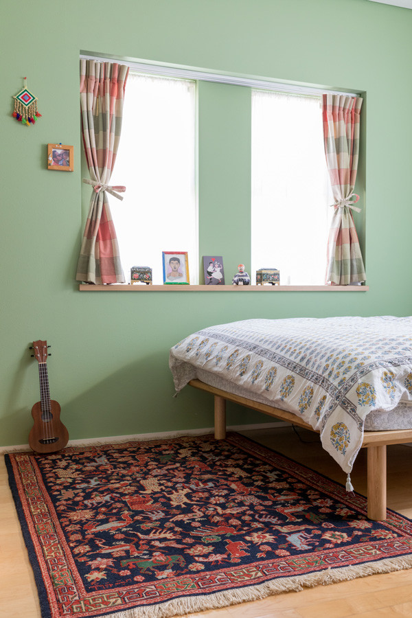 Modelo de dormitorio rústico de tamaño medio con paredes verdes, suelo de madera clara, suelo beige y papel pintado