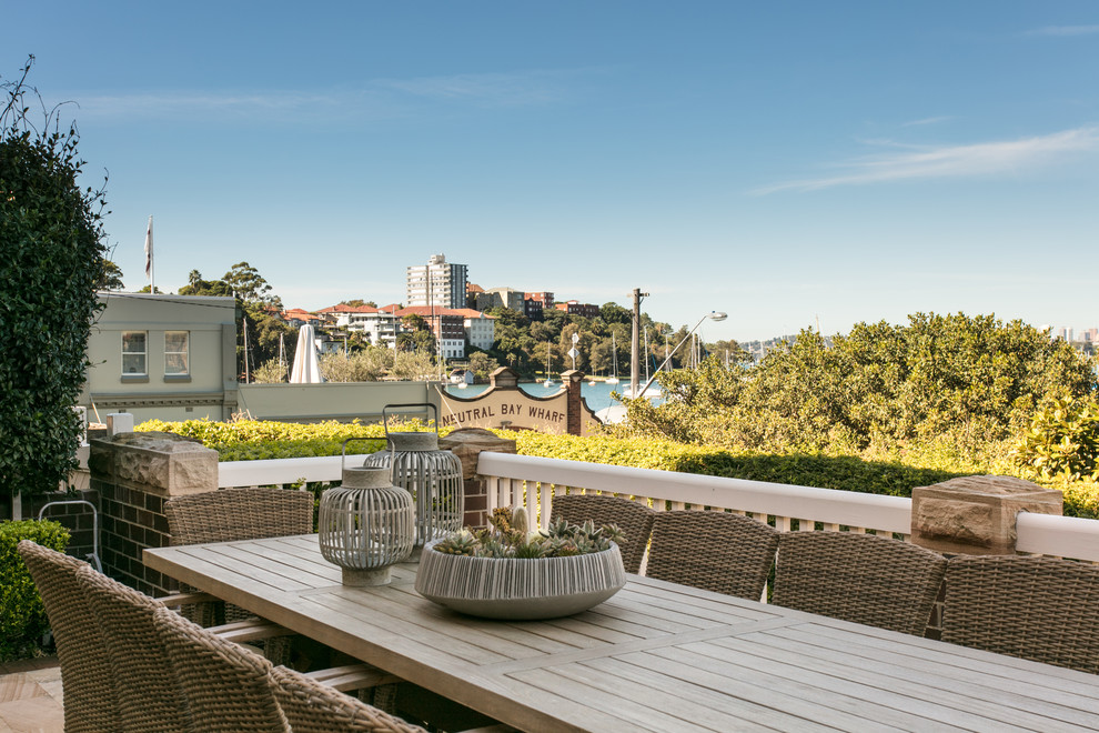 Large beach style backyard patio in Sydney with natural stone pavers and no cover.