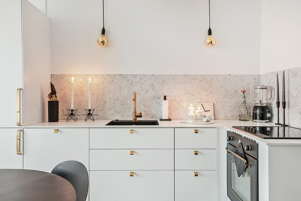 Photo of a mid-sized scandinavian l-shaped open plan kitchen in Stockholm with an undermount sink, flat-panel cabinets, white cabinets, grey splashback, black appliances, no island, light hardwood floors and laminate benchtops.