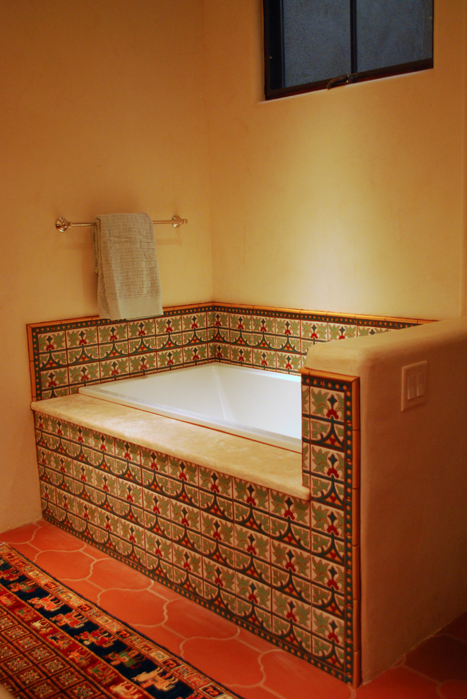 This is an example of a mid-sized kids bathroom in Albuquerque with recessed-panel cabinets, green cabinets, a drop-in tub, multi-coloured tile, ceramic tile, beige walls, terra-cotta floors, an undermount sink and marble benchtops.