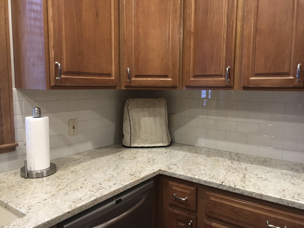 Inspiration for a large transitional u-shaped medium tone wood floor eat-in kitchen remodel with an undermount sink, raised-panel cabinets, medium tone wood cabinets, granite countertops, white backsplash, ceramic backsplash, stainless steel appliances and an island
