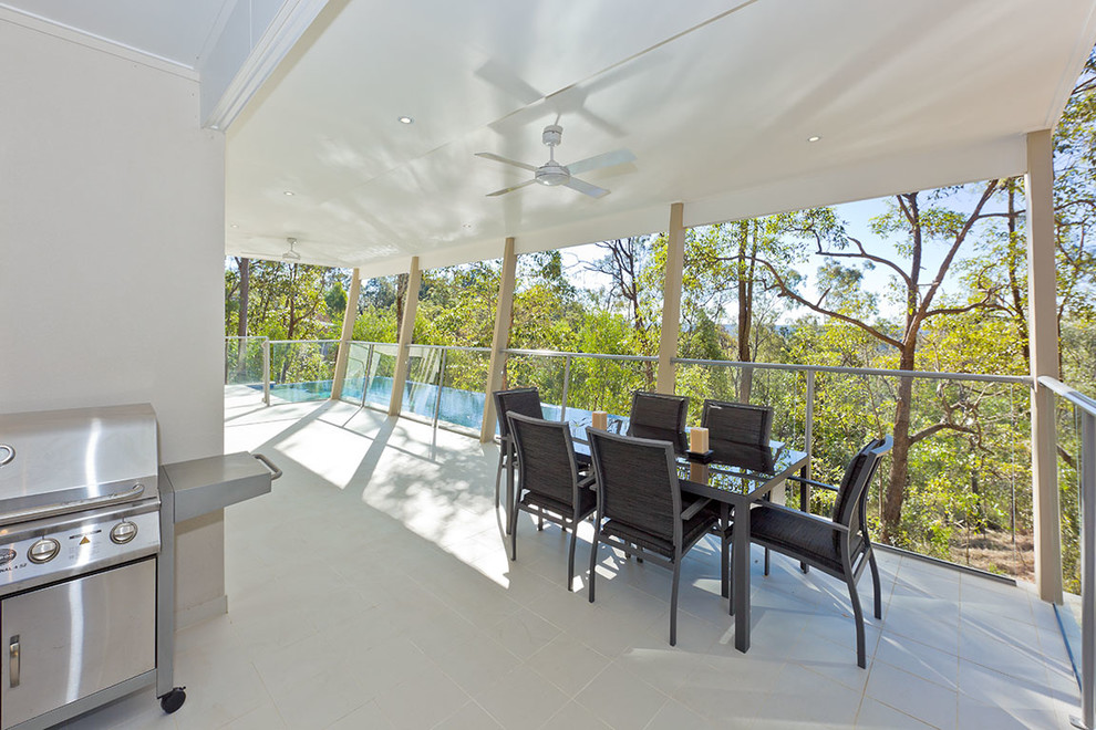 This is an example of a large contemporary deck in Brisbane with a roof extension.