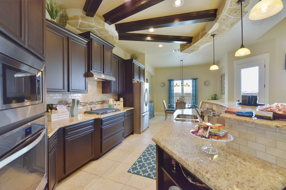 Kitchen - large transitional ceramic tile and beige floor kitchen idea in Austin with a double-bowl sink, raised-panel cabinets, dark wood cabinets, granite countertops, white backsplash, stone tile backsplash and stainless steel appliances